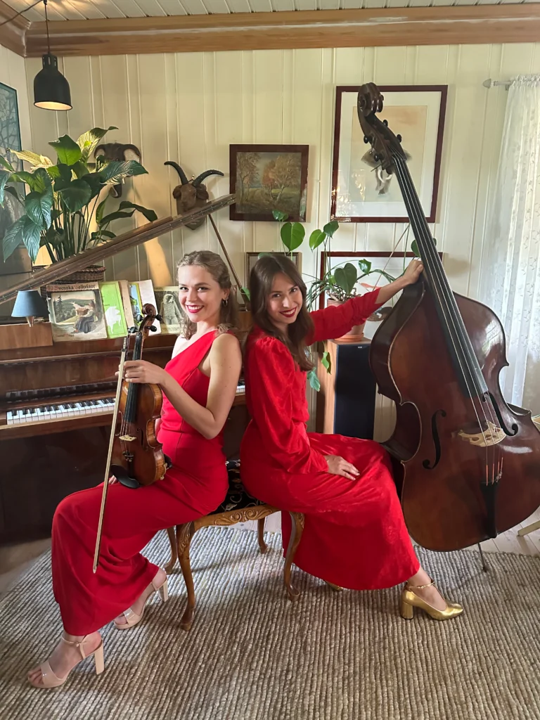 Two women in red dresses playing live music with violin and contrabass at a special occasion in Norway, giving services for private events.