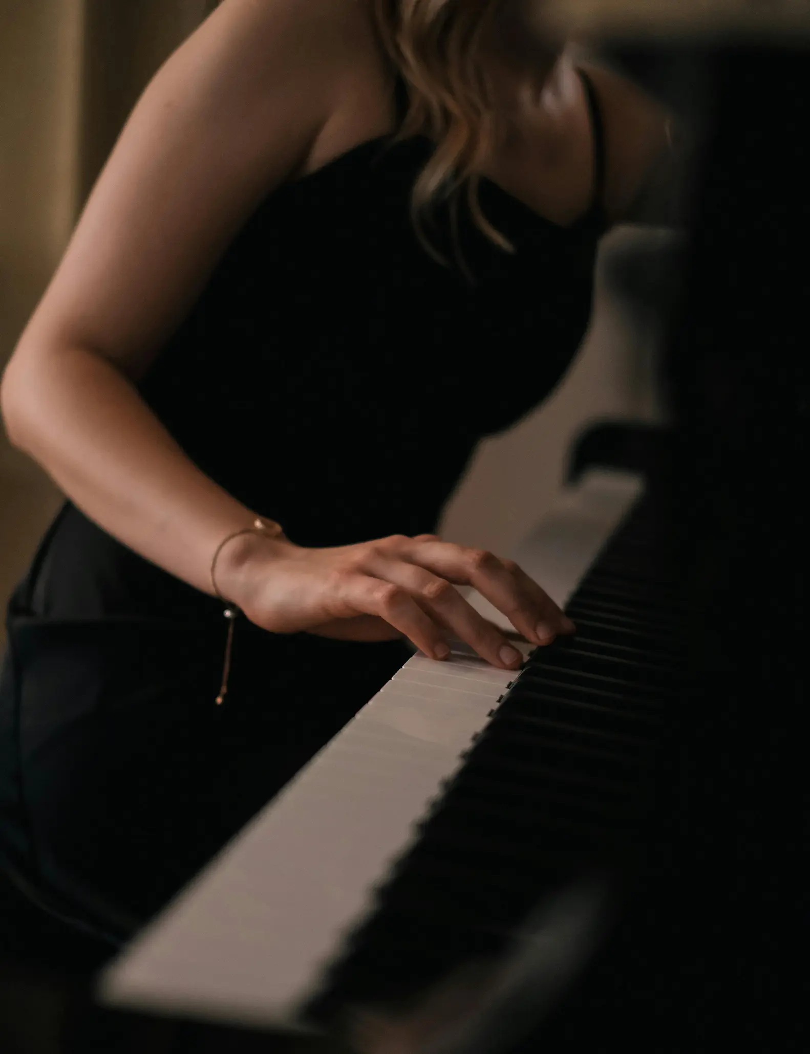 Nærbilde av en kvinnelig pianists hånd som spiller piano under en forestilling i en svart kjole.