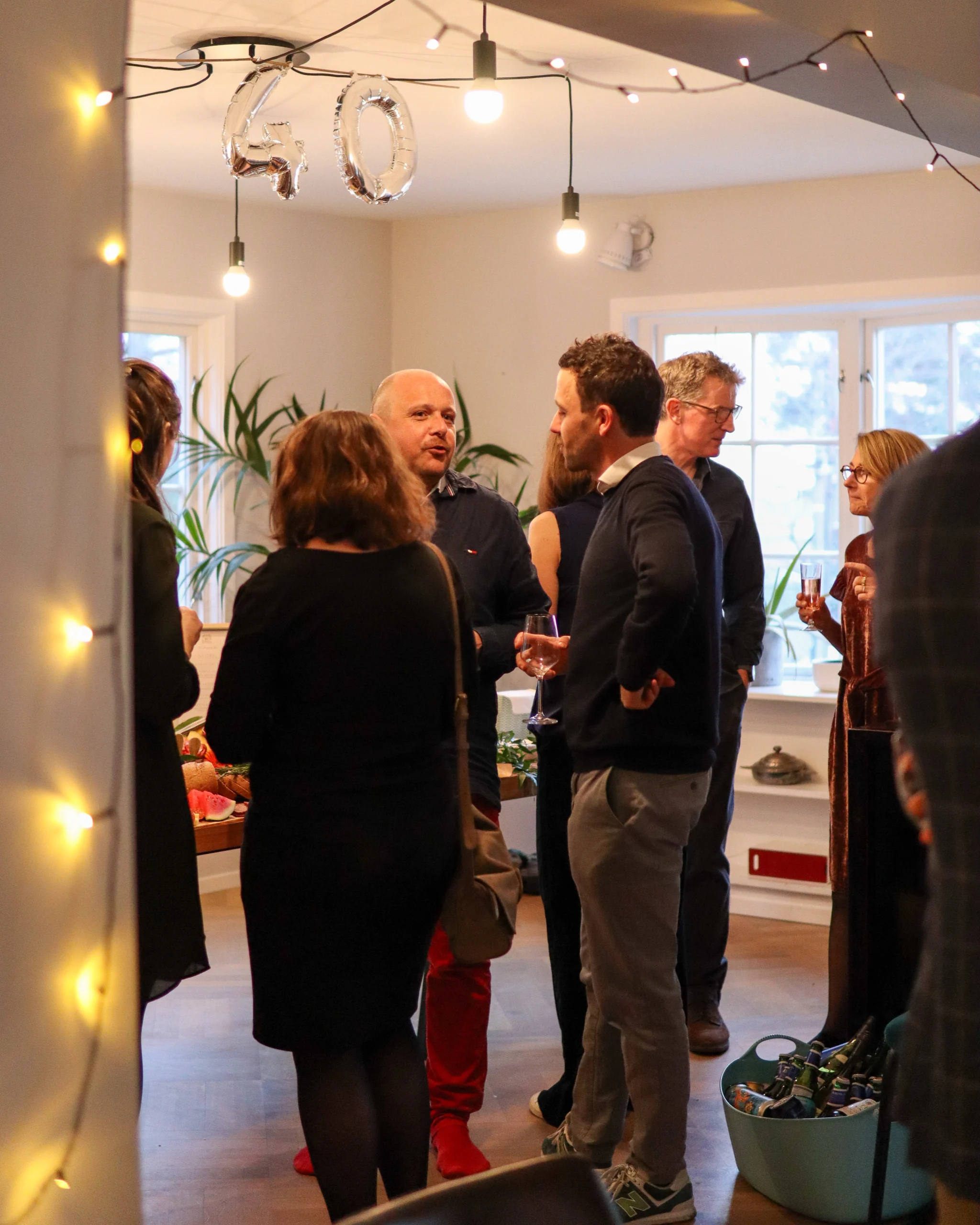 People chatting with each other at a small home birthday party.