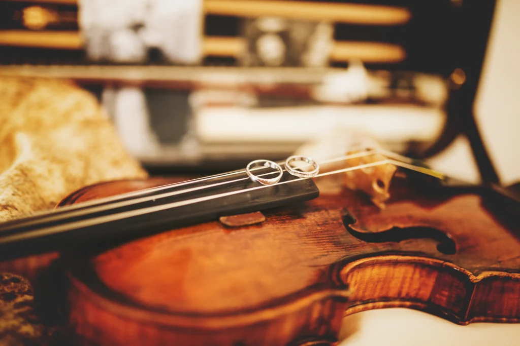 Two sparkling wedding rings resting on violin strings.