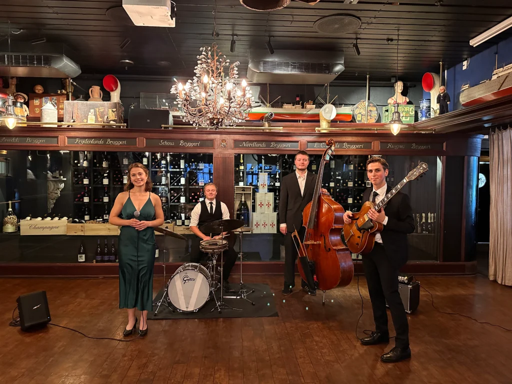 Frankly Swinging band performing live jazz at an upscale venue in Norway, featuring a vocalist, guitarist, double bassist, and drummer