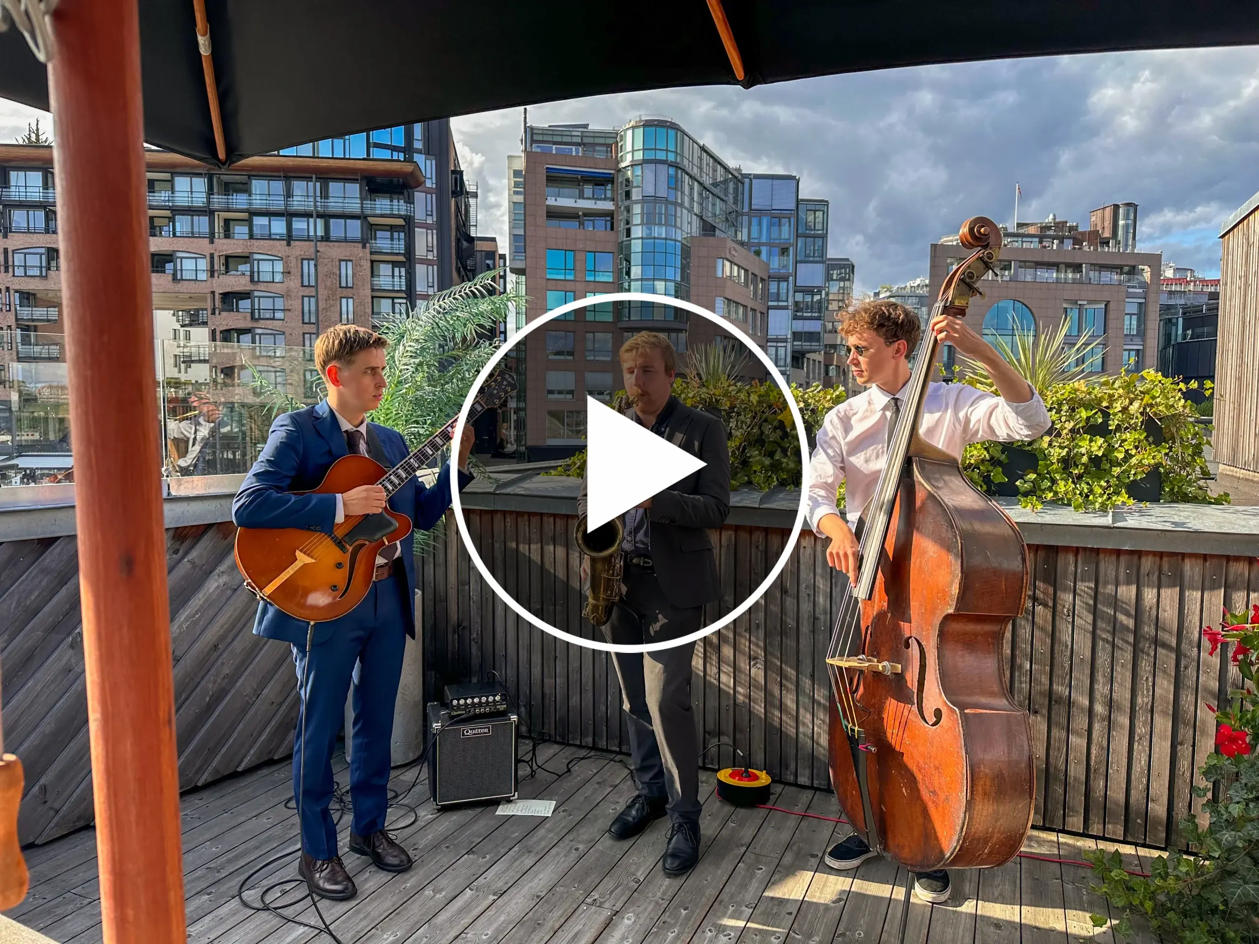 En trio som fremfører live musikk på et privat arrangement på et hustak i Norge.