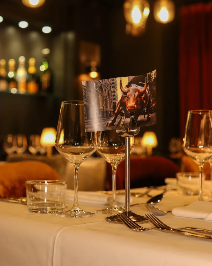 Elegant dining table set up for a Romslo Entertainment event, featuring wine glasses and a decorative bull image.