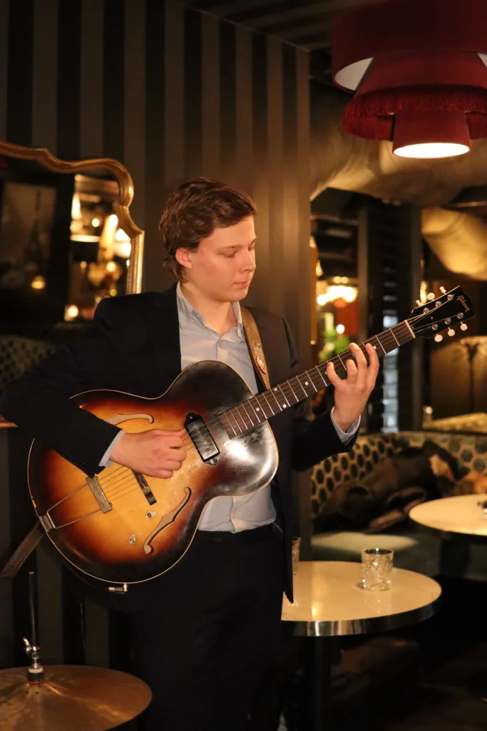 A guitarist playing a jazz guitar at a Romslo Entertainment event in a cozy venue.