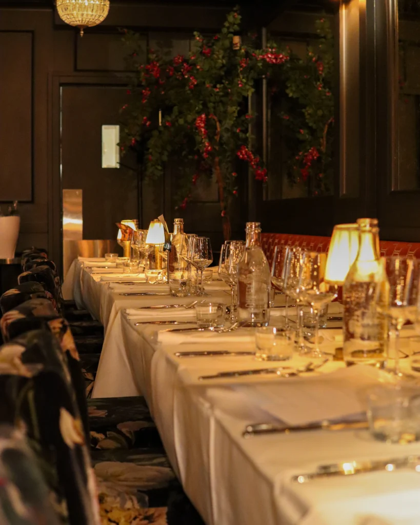 A beautifully decorated long dining table at a Romslo Entertainment event, illuminated by warm lighting.